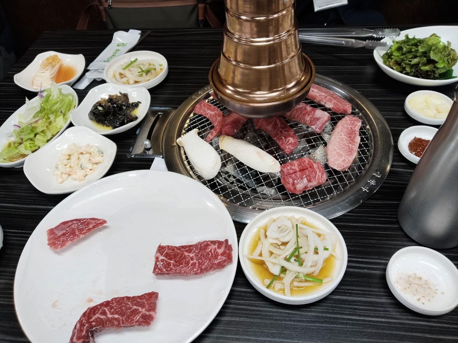 Marbled beef and mushrooms on a charcoal grill with side dishes