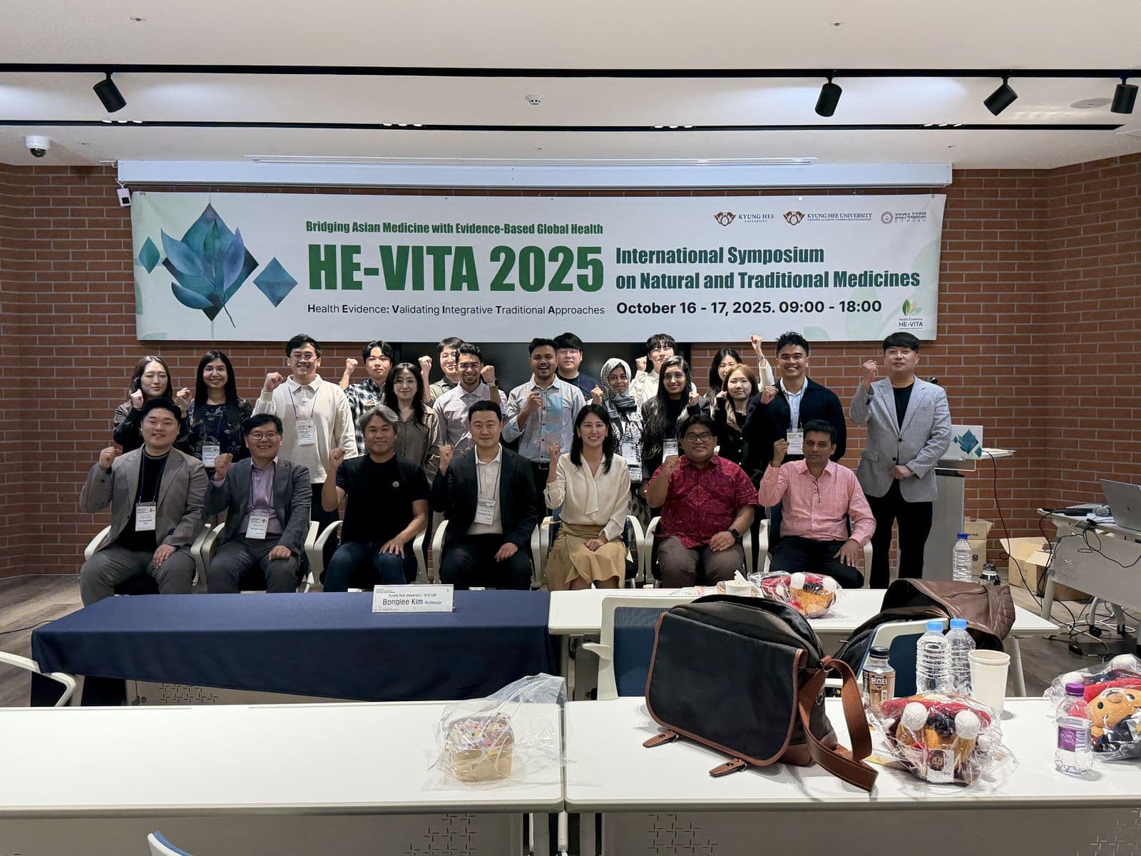 Group photo of HE-VITA 2025 participants under the symposium banner