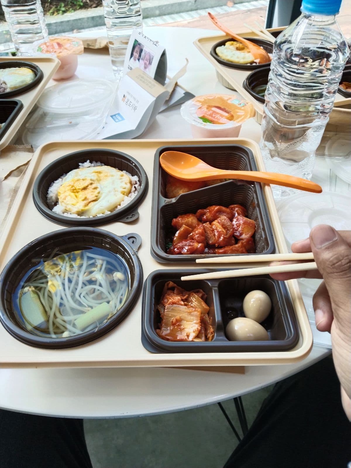 A boxed lunch at the venue with rice, soup, chicken and kimchi