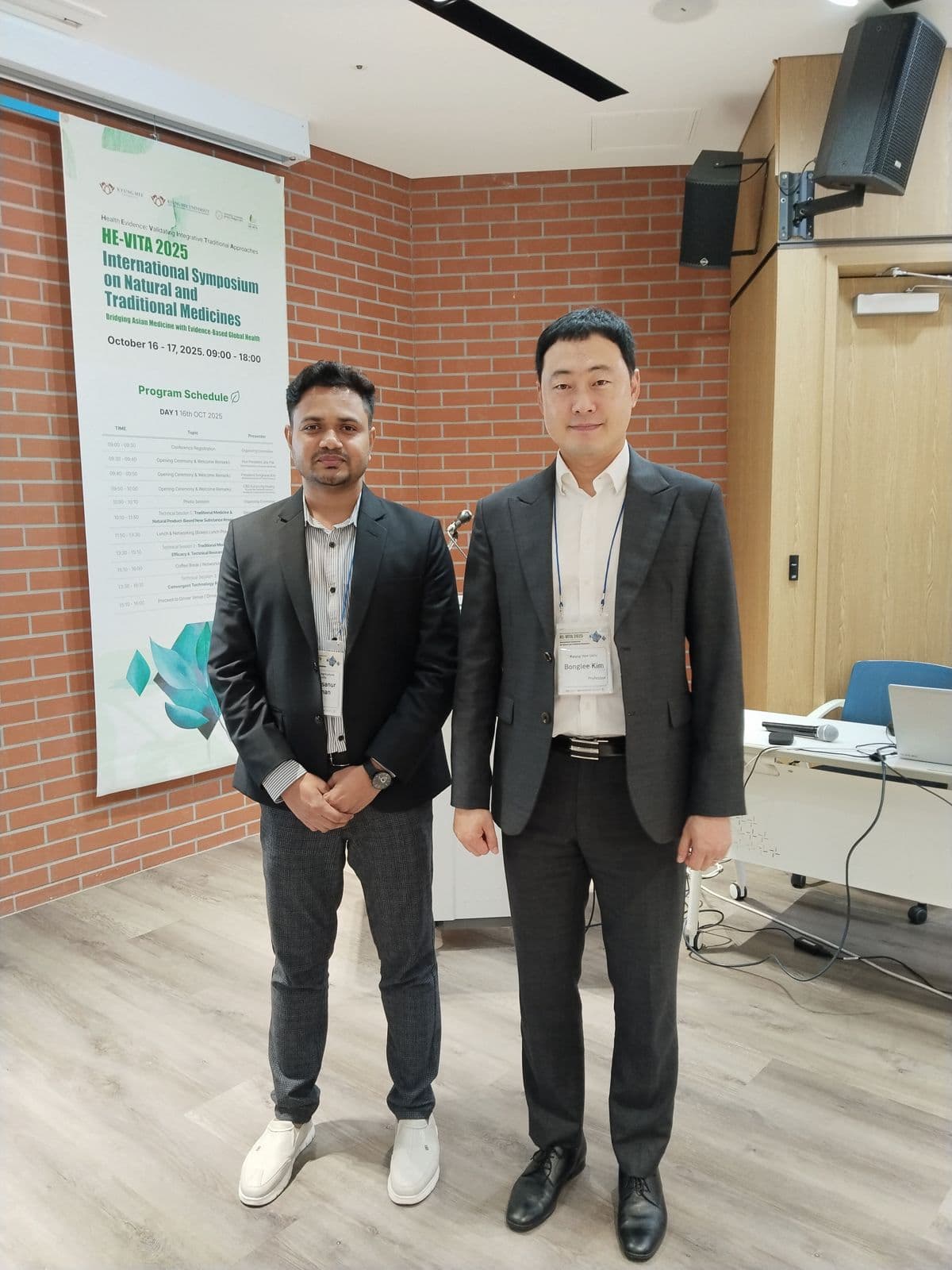 With Professor Bonglee Kim next to the HE-VITA 2025 program poster